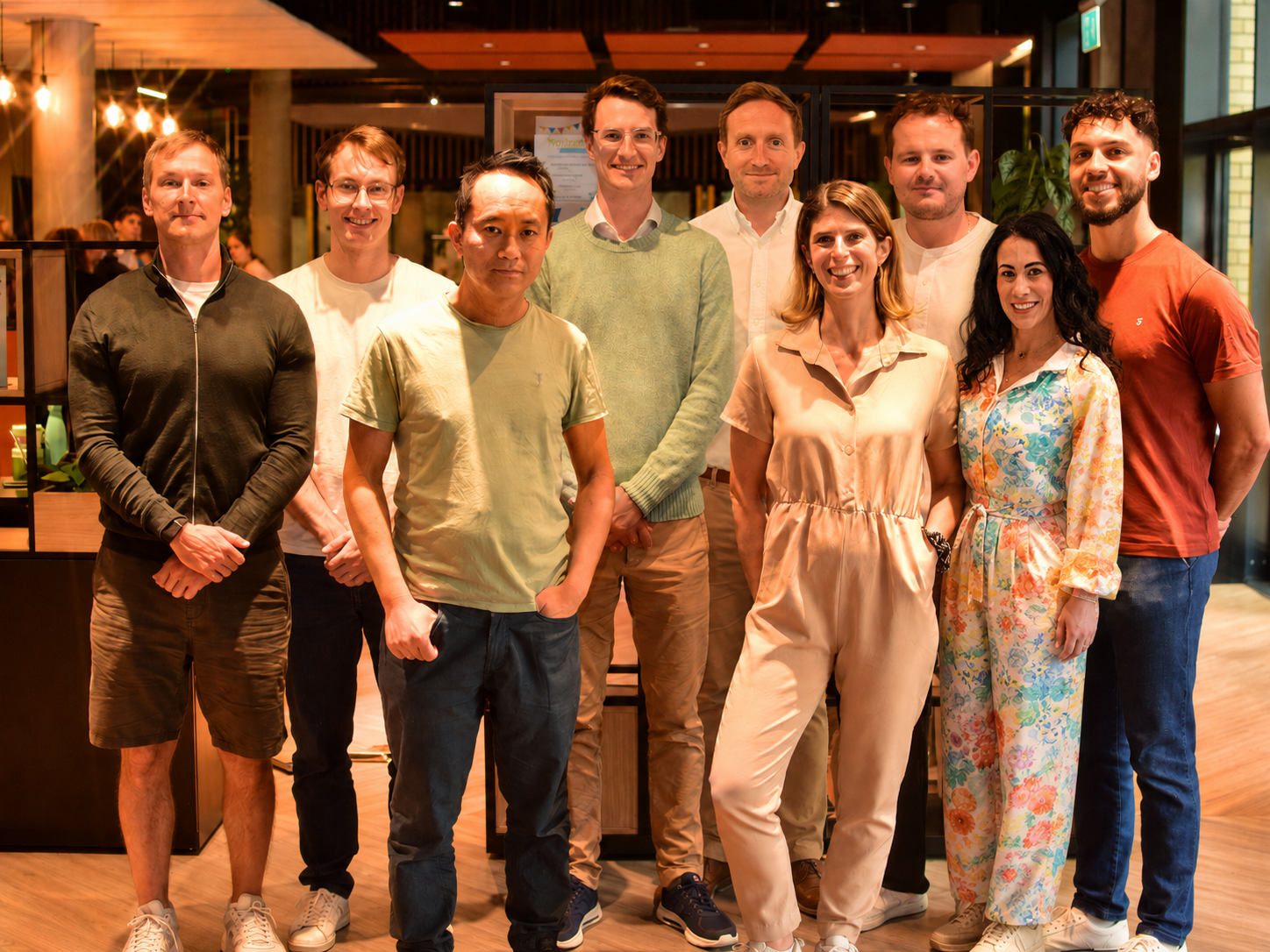 http://Group%20photo%20of%20the%20Permutable%20team%20standing%20together%20in%20a%20modern%20office%20space%20with%20warm%20lighting,%20showing%20nine%20colleagues%20in%20smart-casual%20clothing.